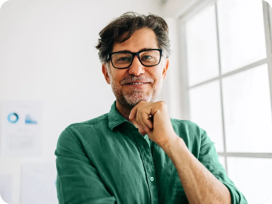Smiling man wearing glasses and a green shirt, representing personalized health plan support and member care.