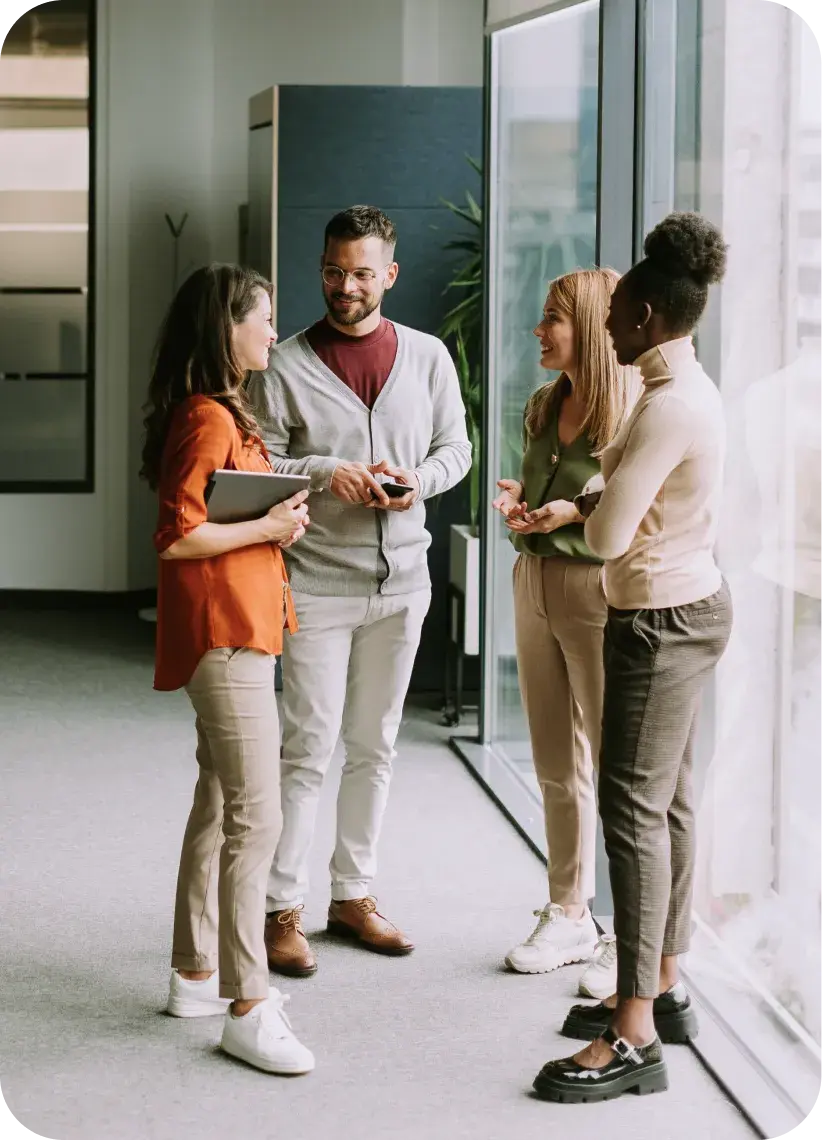 Group of coworkers talking together in an office workspace.