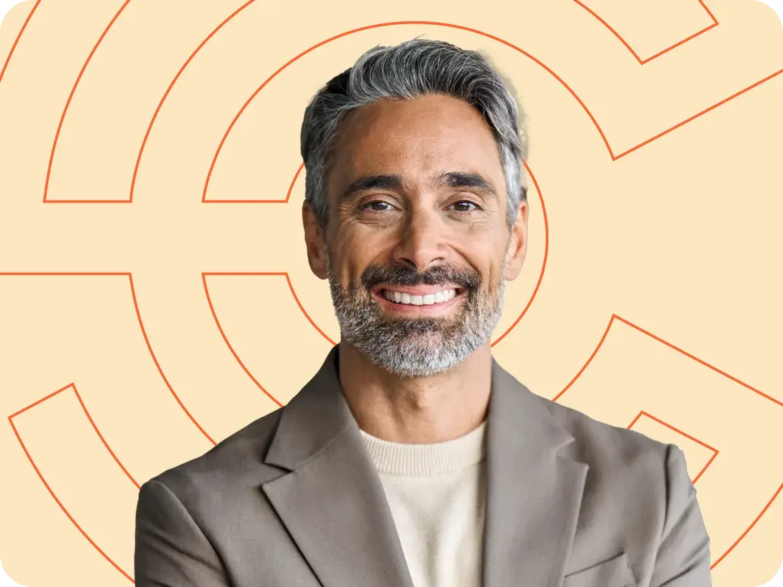 Smiling man with gray hair and beard wearing a light-colored blazer with arms crossed.