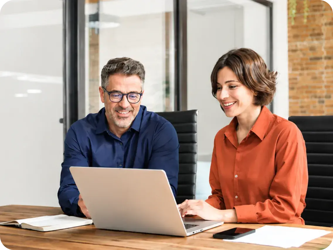 A broker and an employer reviewing cost containment options together on a laptop