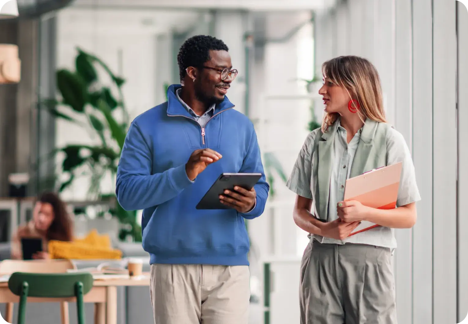Two coworkers walking and talking in an office space.